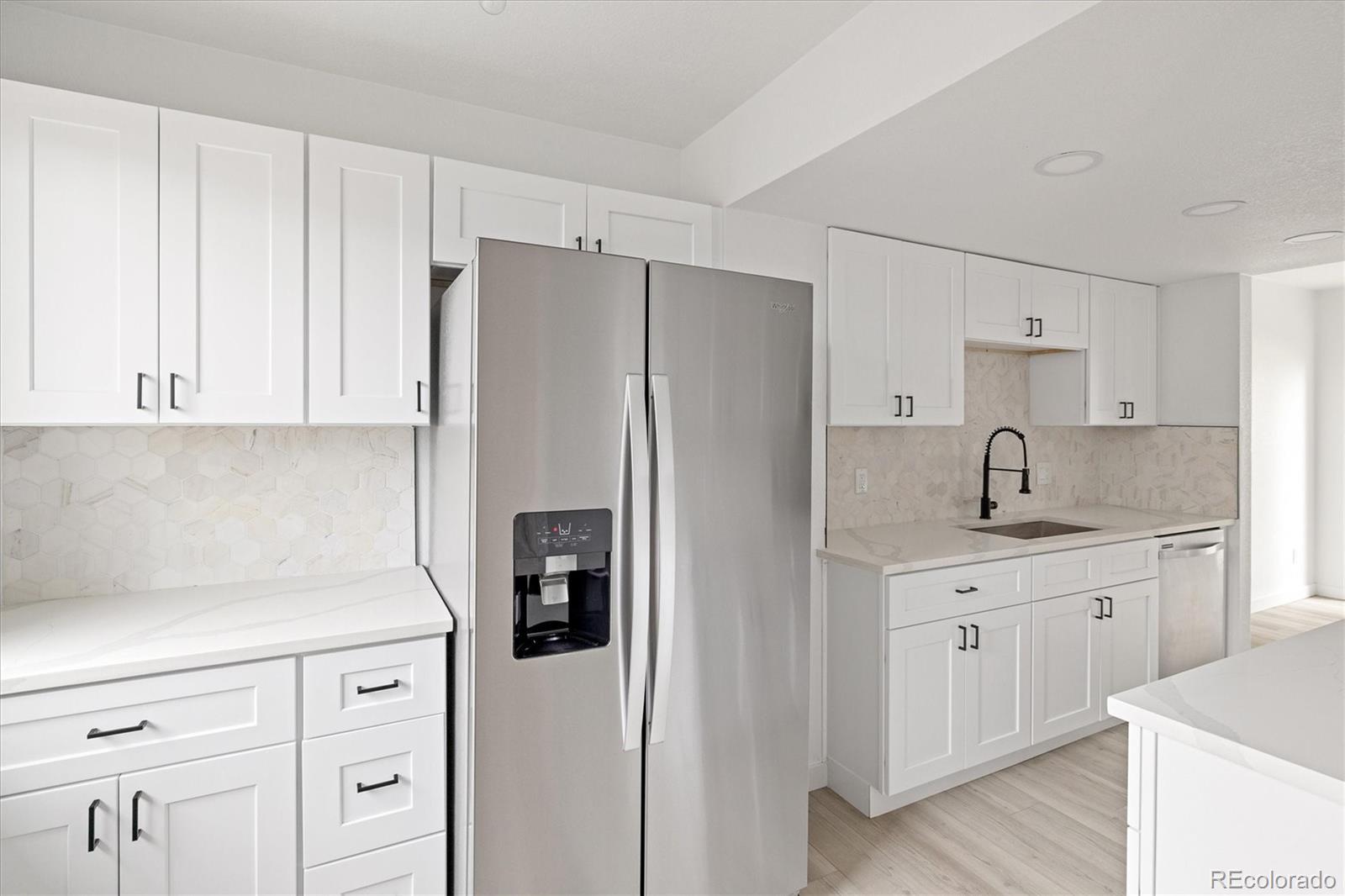 8612 Carr Loop Arvada, CO 80005 - Photo 7 of 35 a kitchen with white cabinets and refrigerator