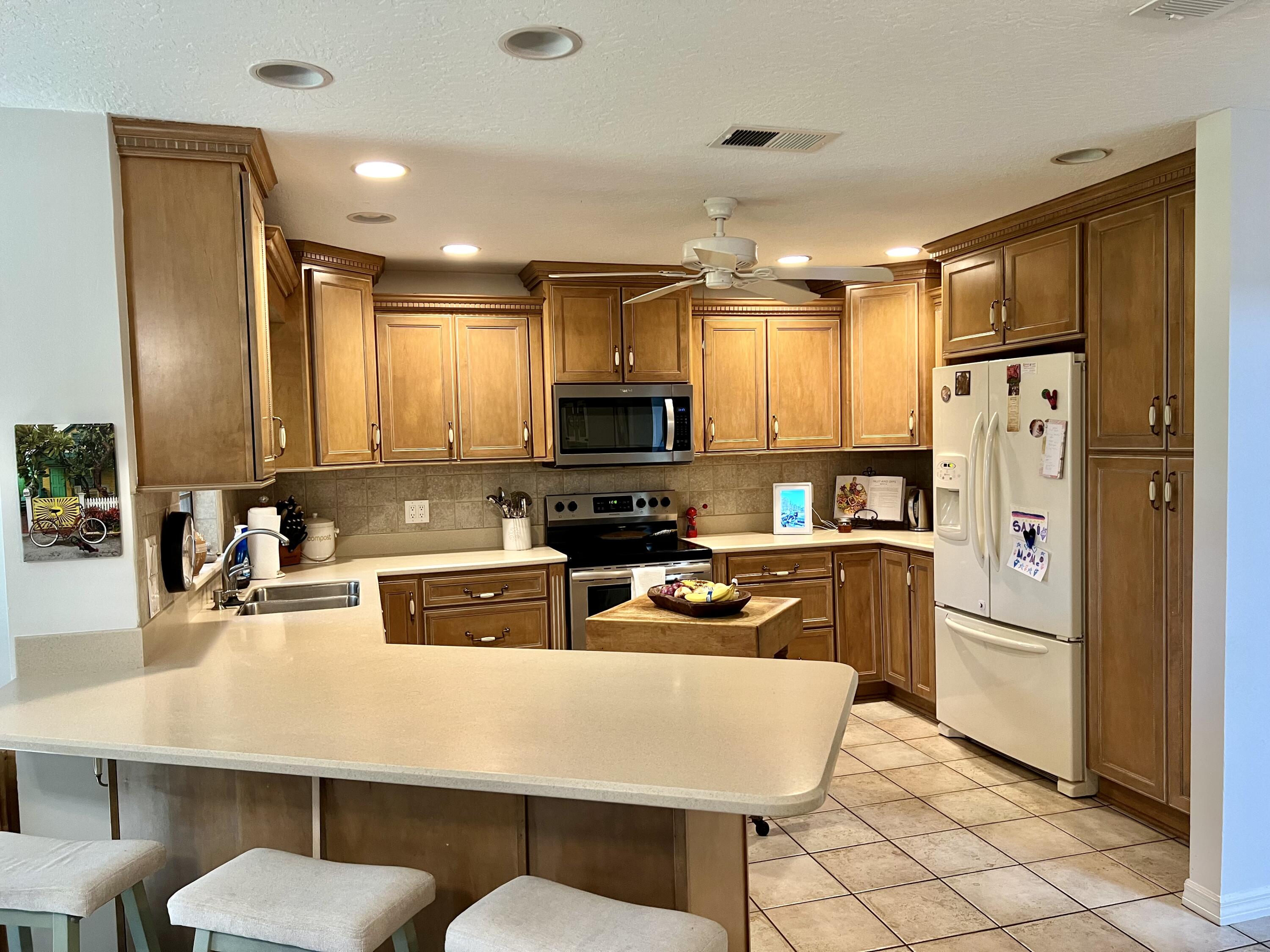 410 Rio Casa Drive South Indialantic, FL 32903 - Photo 3 of 25 a kitchen with a refrigerator a stove a sink a dining table and chairs with wooden floor