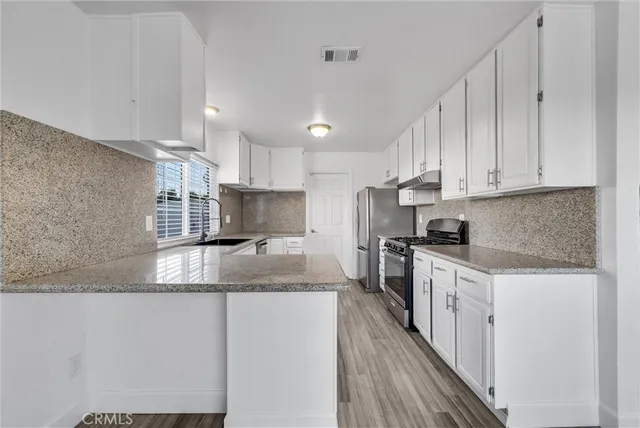 a kitchen with stainless steel appliances granite countertop a stove a sink and white cabinets