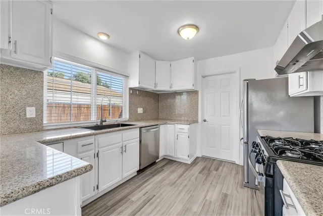a kitchen with granite countertop a sink cabinets stainless steel appliances and a counter space