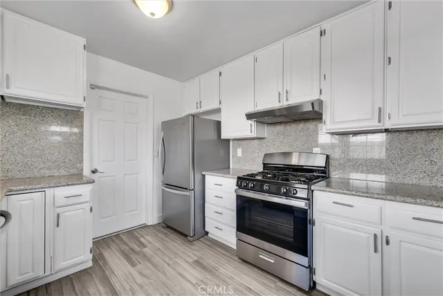a kitchen with white cabinets and stainless steel appliances