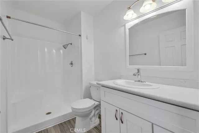 a bathroom with a granite countertop sink a toilet a shower and a mirror