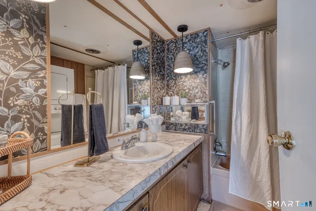 a bathroom with a granite countertop sink a mirror and shower