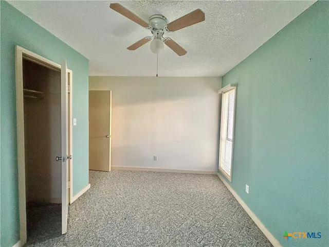 an empty room with fan and windows