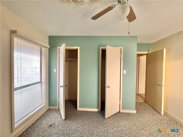 a view of empty room with windows and ceiling fan