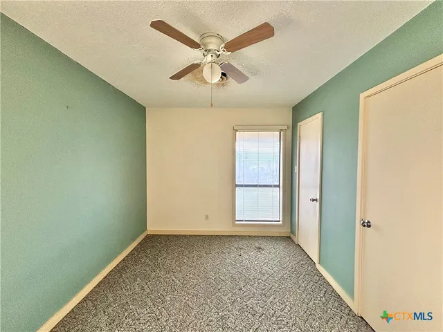 an empty room with ceiling fan and window