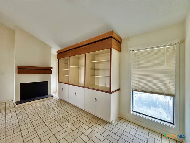 a view of an empty room with window and chandelier fan