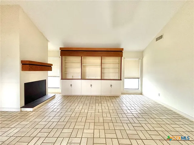 a view of empty room with wooden floor and fireplace