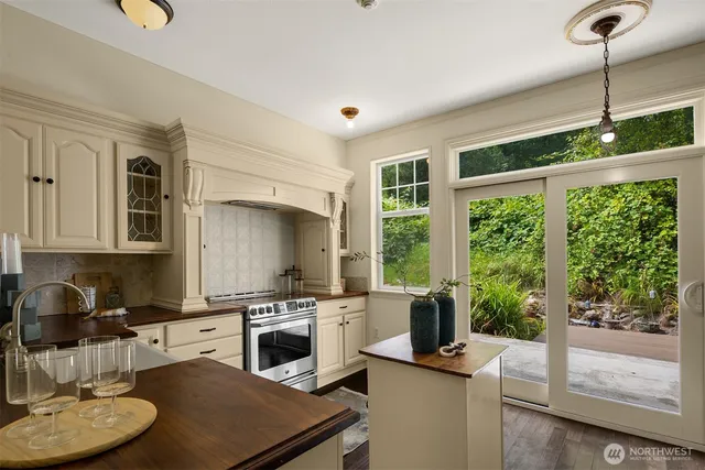 a kitchen with a stove a sink dishwasher a dining table and chairs with wooden floor