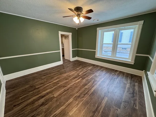a view of an empty room with window and wooden floor