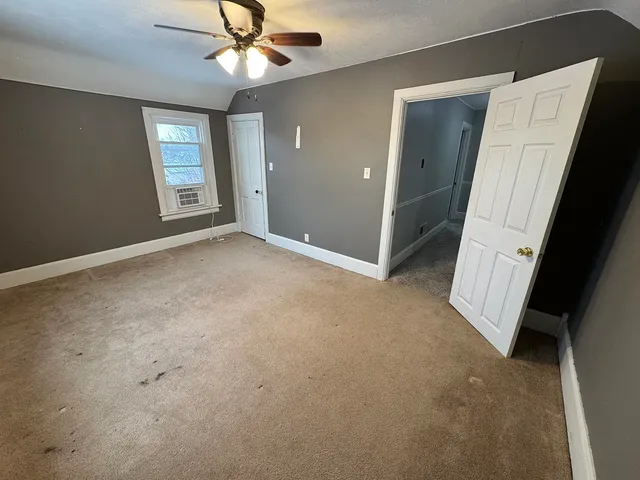 an empty room with wooden floor closet and fan