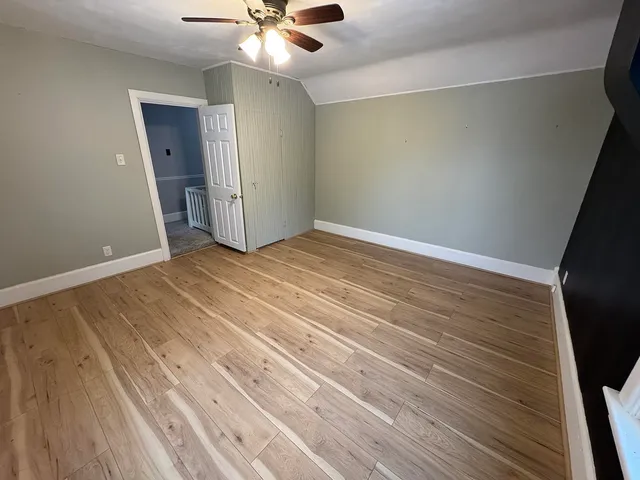 a view of an empty room with window and wooden floor