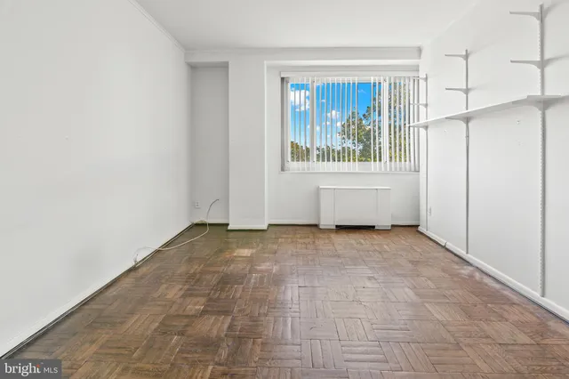 a view of an empty room with window and cabinet