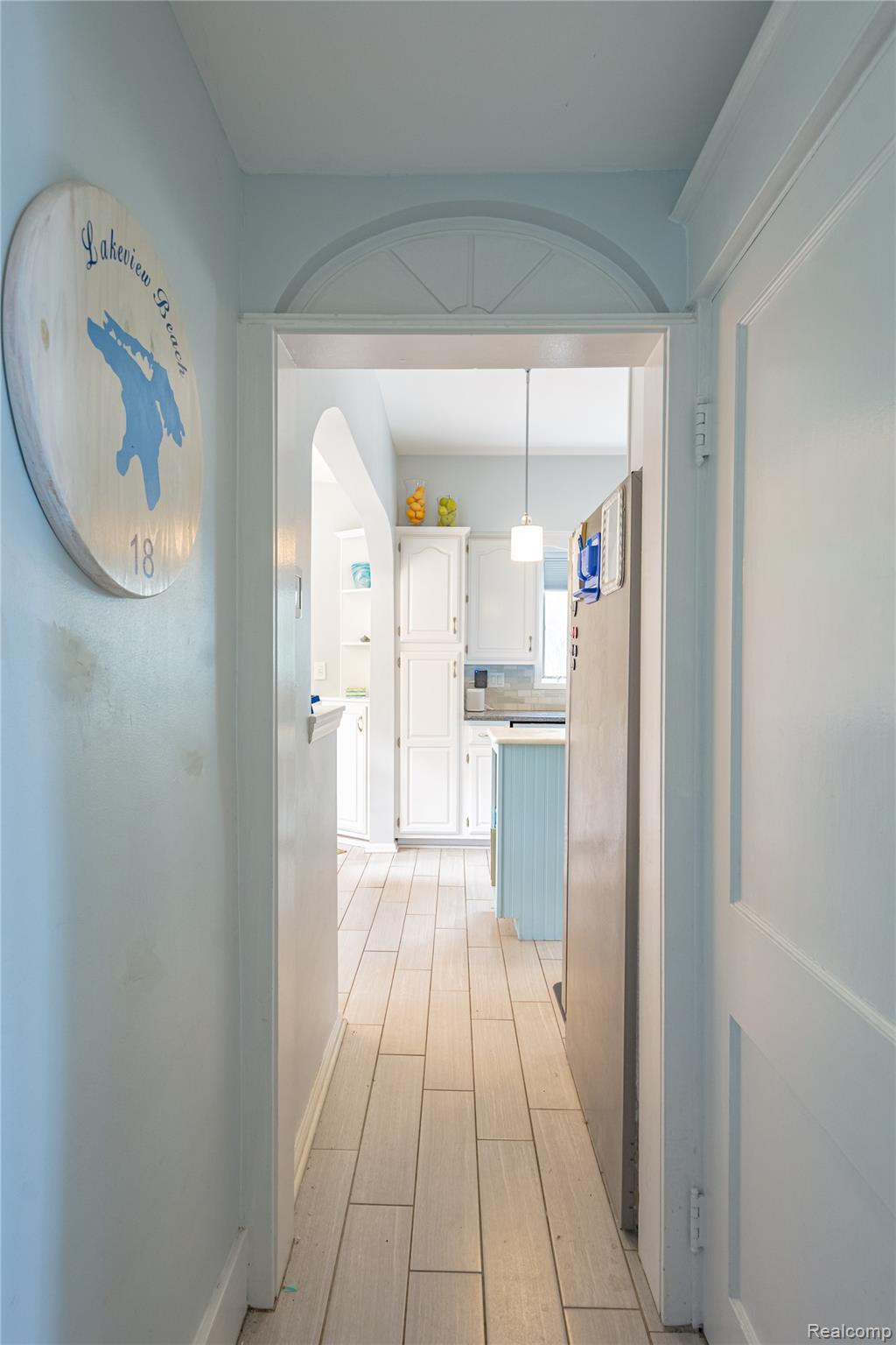 5630 Lakeshore Road Fort Gratiot, MI 48059 - Photo 11 of 49 Hallway featuring light wood-finish flooring, a decorative arched doorway, and light-colored walls