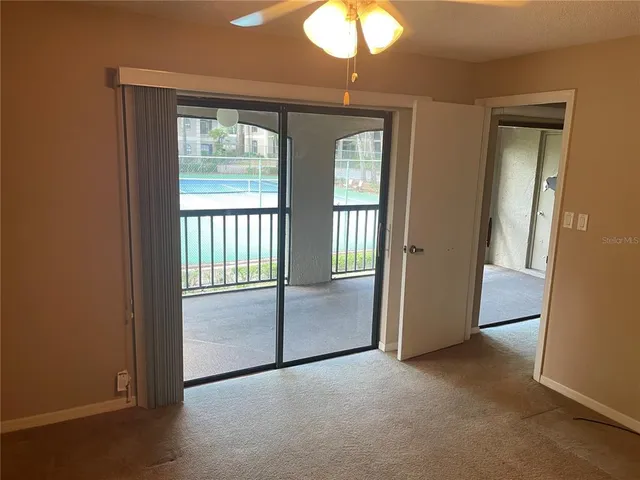 an empty room that has a large window and chandelier fan