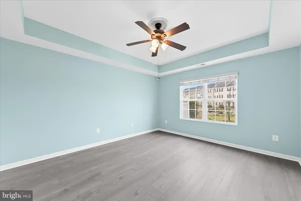 an empty room with wooden floor and ceiling fan