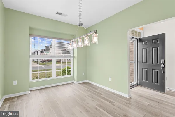 a kitchen with stainless steel appliances granite countertop a refrigerator a stove top oven a sink dishwasher a dining table and chairs with wooden floor