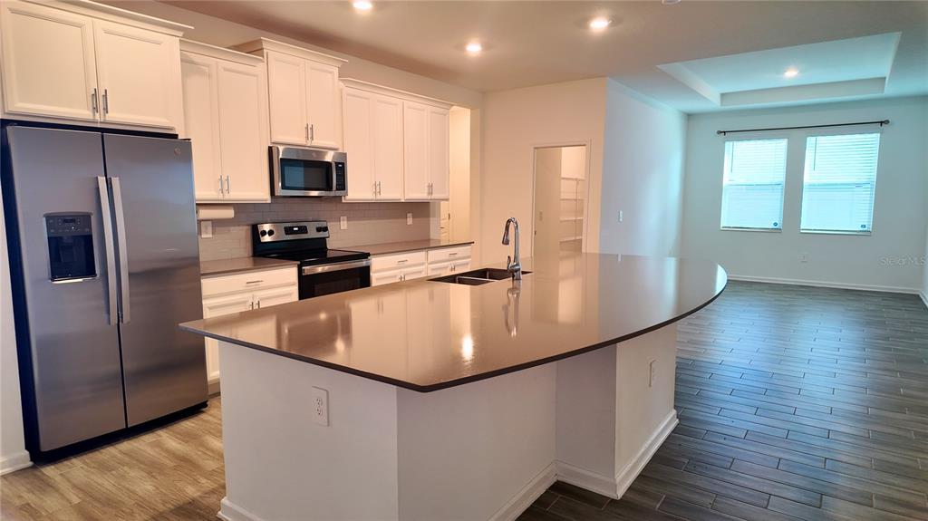 6366 Lakepine Street St. Cloud, FL 34771 - Photo 8 of 22 a kitchen with stainless steel appliances a refrigerator a sink a stove cabinets and wooden floor
