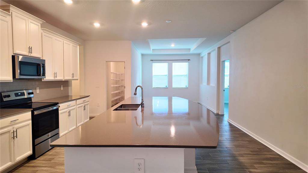 6366 Lakepine Street St. Cloud, FL 34771 - Photo 9 of 22 a large kitchen with stainless steel appliances granite countertop a sink a stove counter space and wooden floor
