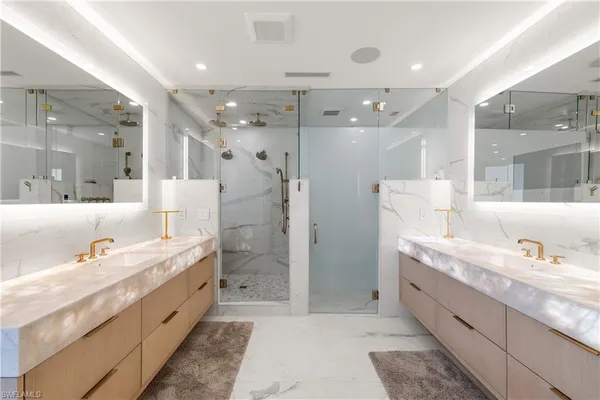 a large bathroom with a granite countertop double vanity sink a large mirror and shower