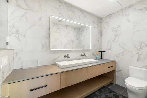 a bathroom with a granite countertop sink mirror vanity and toilet