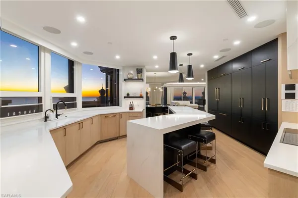 a large kitchen with a table chairs sink and refrigerator