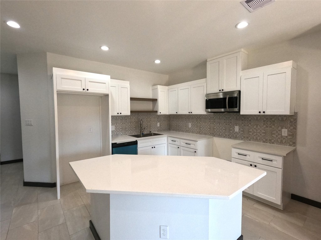 5334 Rapido Road Houston, TX 77033 - Photo 3 of 13 a kitchen with kitchen island a sink a stove a refrigerator and white cabinets