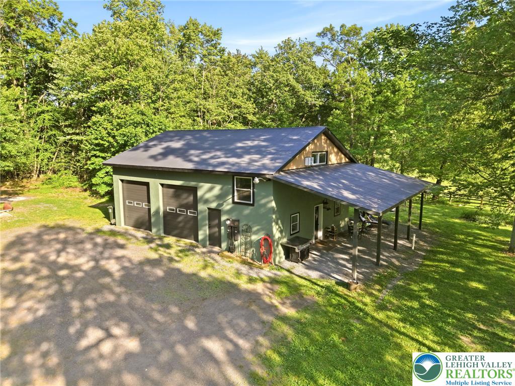 9033 Loop Road Slatington, PA 18080 - Photo 2 of 53 Green siding and a metal roof complement this home set amidst a natural, wooded landscape.
