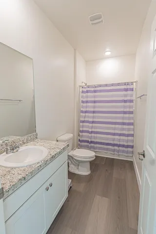 a bathroom with a granite countertop toilet a sink and a mirror