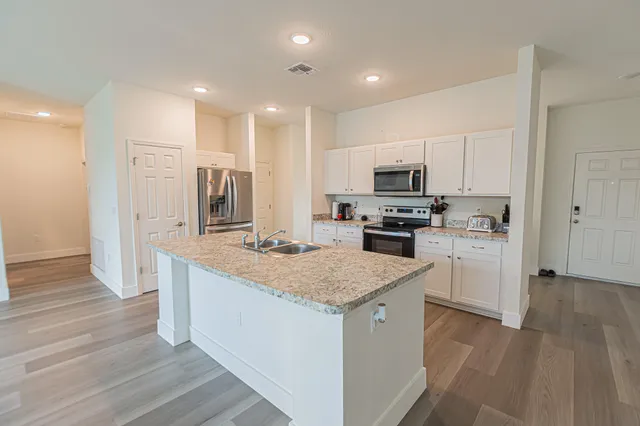 a kitchen with stainless steel appliances granite countertop a stove top oven a sink and a refrigerator