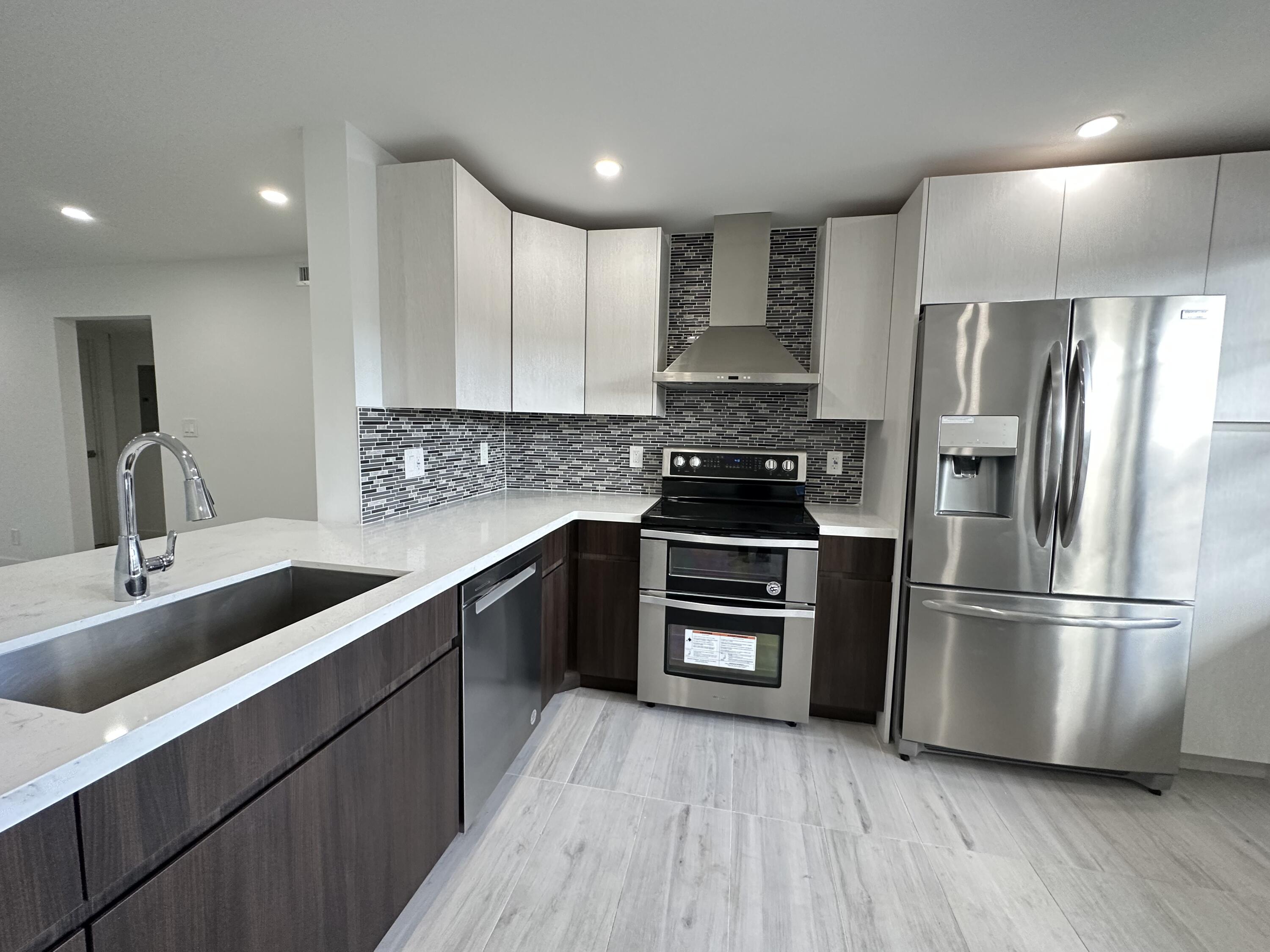 a kitchen with kitchen island a sink wooden floor and stainless steel appliances