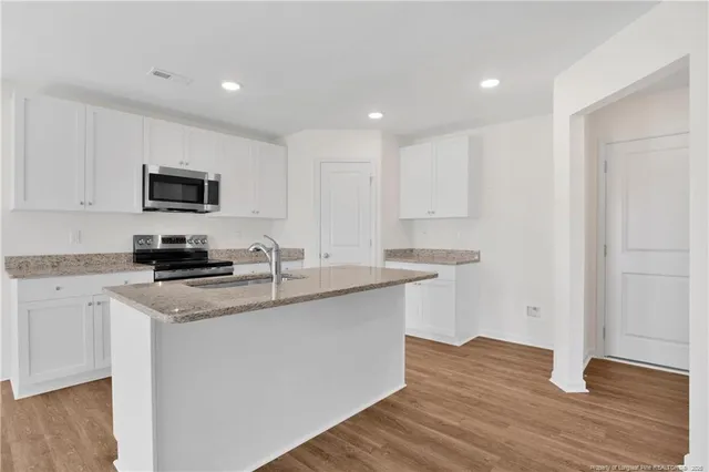 a kitchen with a sink and a stove top oven with wooden floor