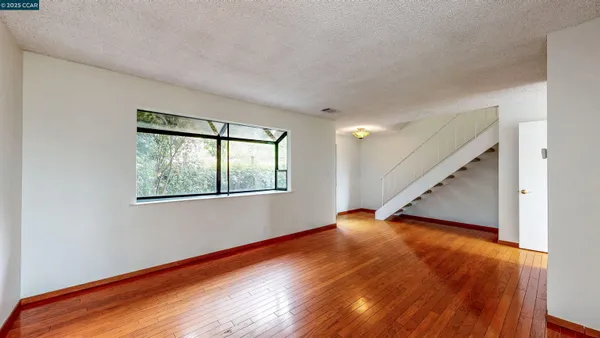a view of an empty room with wooden floor and a window