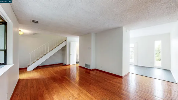 an empty room with wooden floor and windows