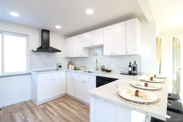 a kitchen with granite countertop stainless steel appliances a sink a stove a refrigerator and white cabinets with wooden floor