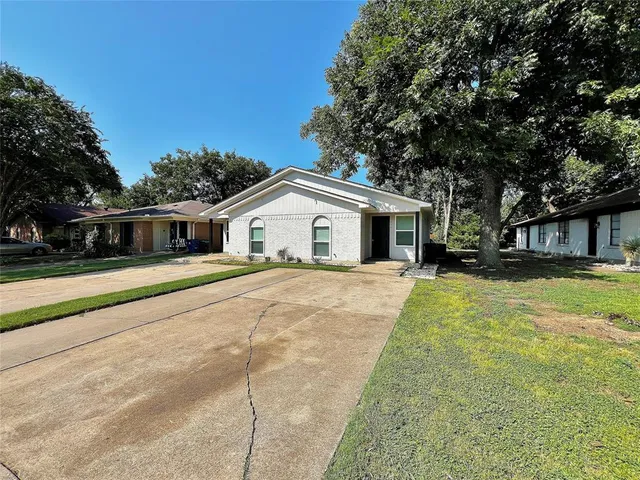 a white house with a large tree next to a yard