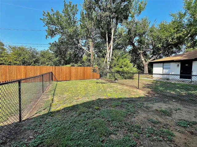 a view of backyard with large trees and wooden fence