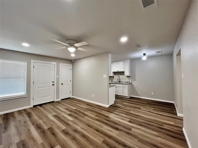a view of an empty room with wooden floor and a window