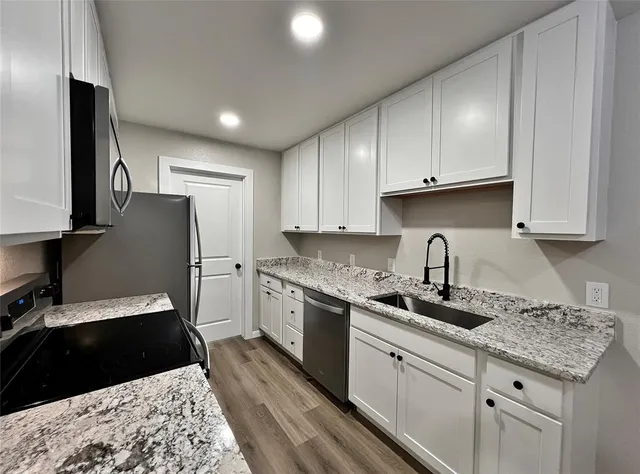 a kitchen with granite countertop a sink stainless steel appliances and cabinets