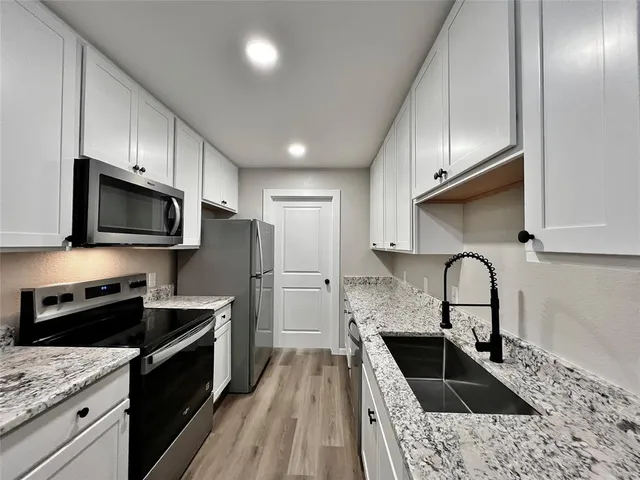 a kitchen with granite countertop a stove a sink and a microwave