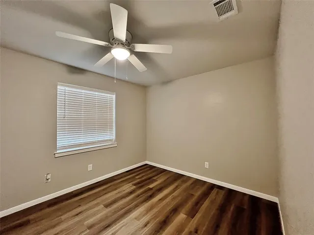 an empty room with a window and a fan
