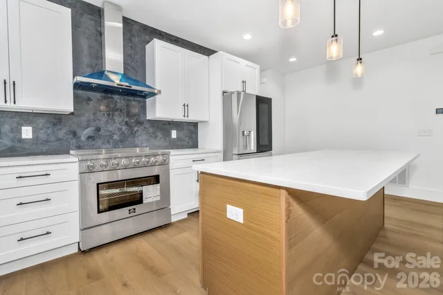 a kitchen with stainless steel appliances kitchen island granite countertop a stove a sink and a refrigerator