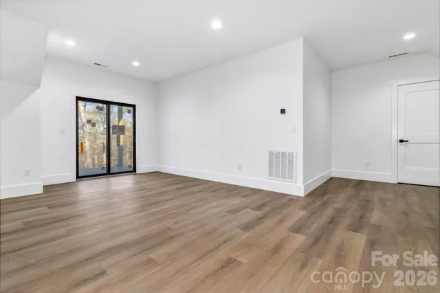 a view of an empty room with wooden floor and window