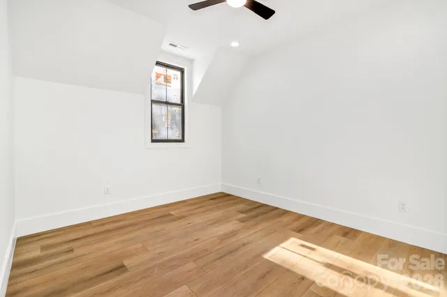 an empty room with wooden floor cabinet and windows