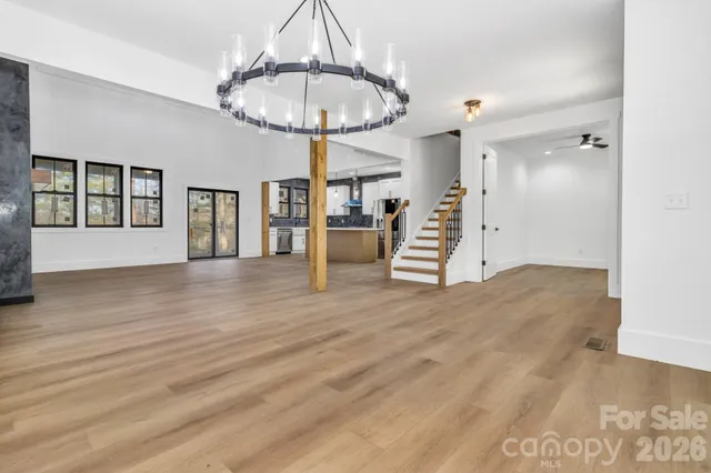 a view of empty room with wooden floor chandelier and entryway