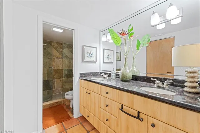 a bathroom with a granite countertop sink a toilet a mirror and shower