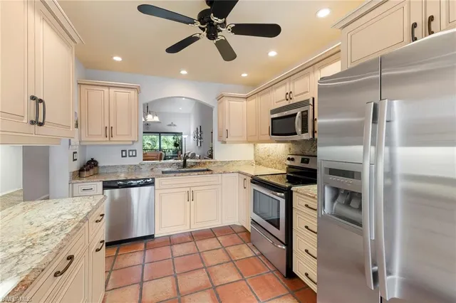a kitchen with stainless steel appliances granite countertop a stove top oven a sink a refrigerator and white cabinets