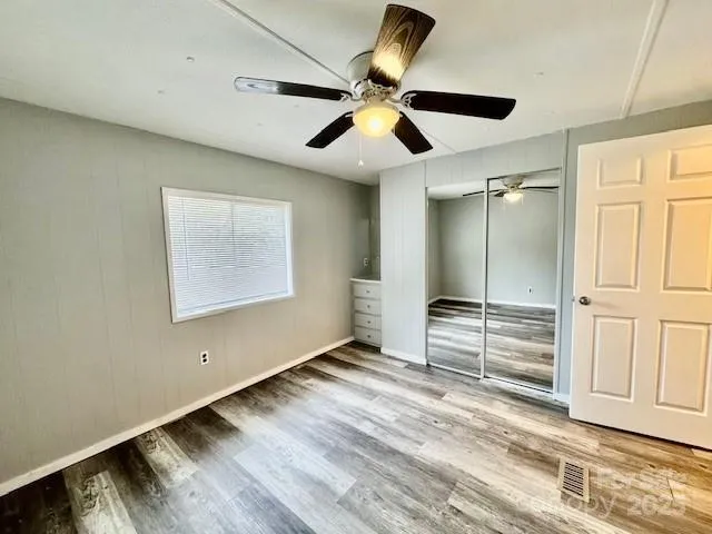 an empty room with wooden floor ceiling fan and windows