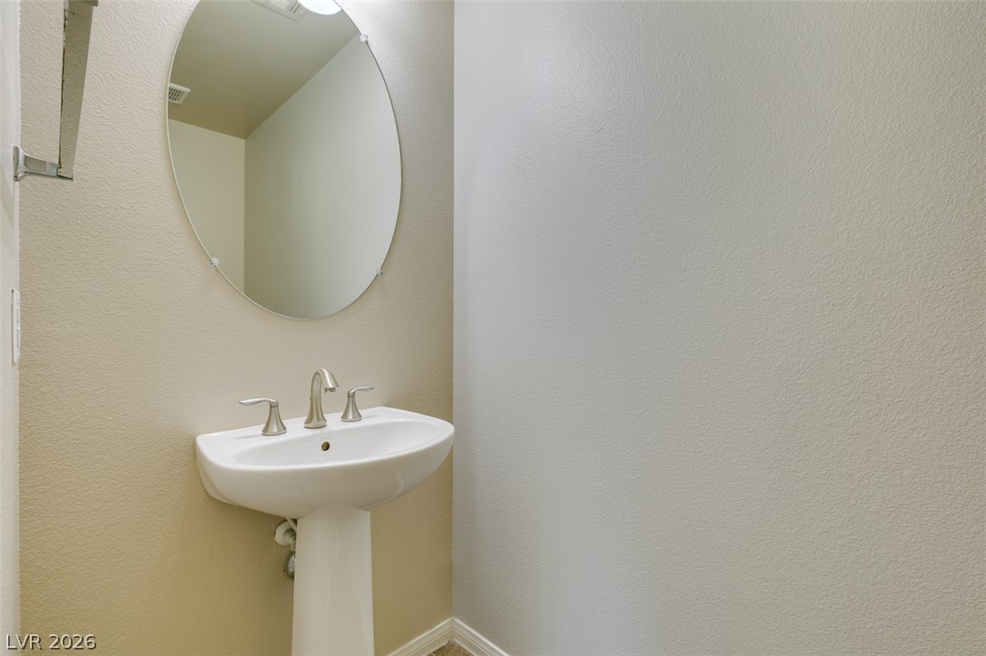 8937 Caledon Ridge Court Las Vegas, NV 89149 - Photo 27 of 43 A sleek pedestal sink and mirror create a functional, modern bathroom space.