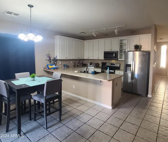 a kitchen with stainless steel appliances granite countertop a sink a stove a refrigerator with a dining table and chairs